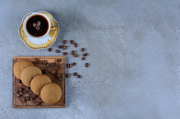 Round fresh sweet cookies with coffee beans and a glass cup of tea.