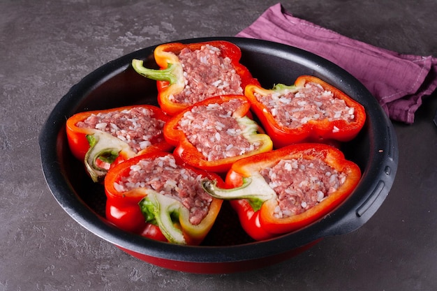 Round frying pan with stuffed raw pepper on a gray background