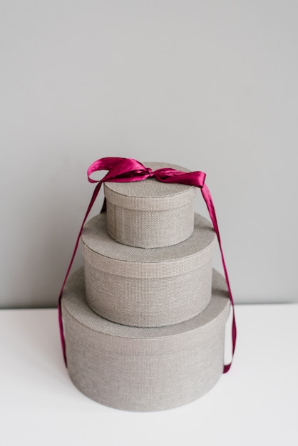 Round gift boxes tied with purple satin ribbon on a gray