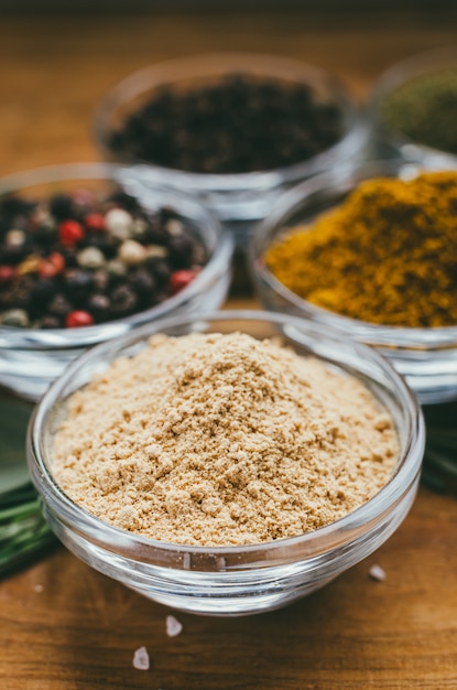 Round glass bowl with spice on wooden table. ground ginger.