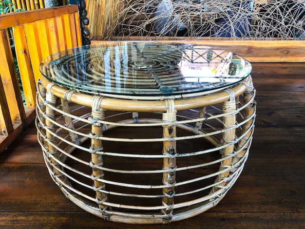 A round glass coffee table with a wooden frame and a rope hanging on the wall.