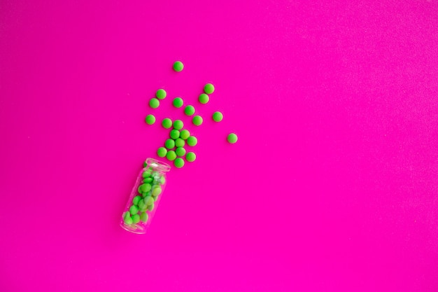 Round green pills on a pink background top view. Chlorella tablets are food supplements. Spirulina in pill form.