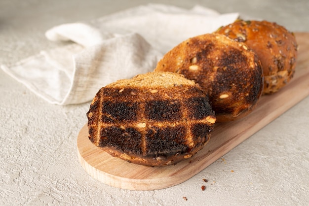 Round grilled cereal buns lie on a wooden board