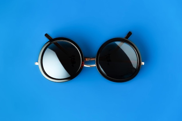 Round hipster sunglasses on blue background in minimalist style