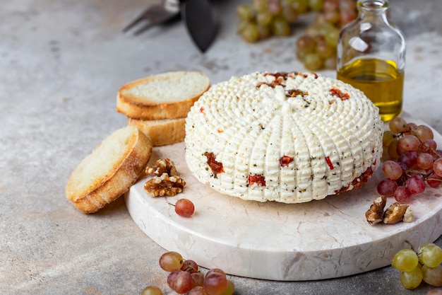 Round homemade cheese with herbs and dried tomatoes