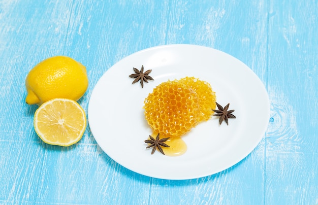 Round honeycombs, lemon and anise lie on a plate on a blue .