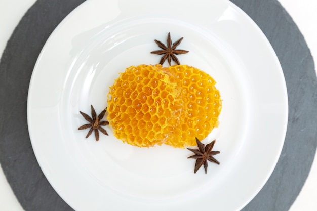 Round honeycombs lie on a plate on a white wooden .