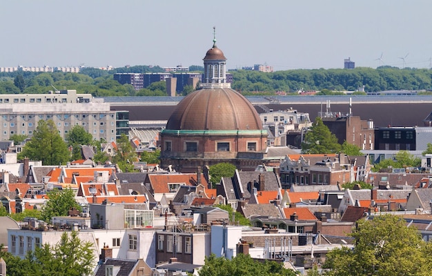 Round Koepelkerk with copper dome next to Singel canal Roofs and facades of Amsterdam City view from the bell tower of the church Westerkerk Holland Netherlands