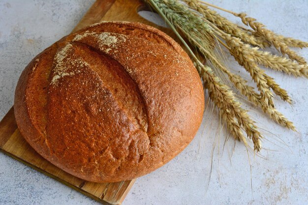 round loaf of bread isolated decorated with ears of wheat, close-up