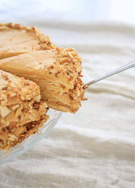 Round napoleon cake with caramel cream and a cut off piece on a white background copy space