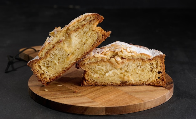 Round pastry with almonds and butter sprinkled with powdered sugar on the table puff pastry