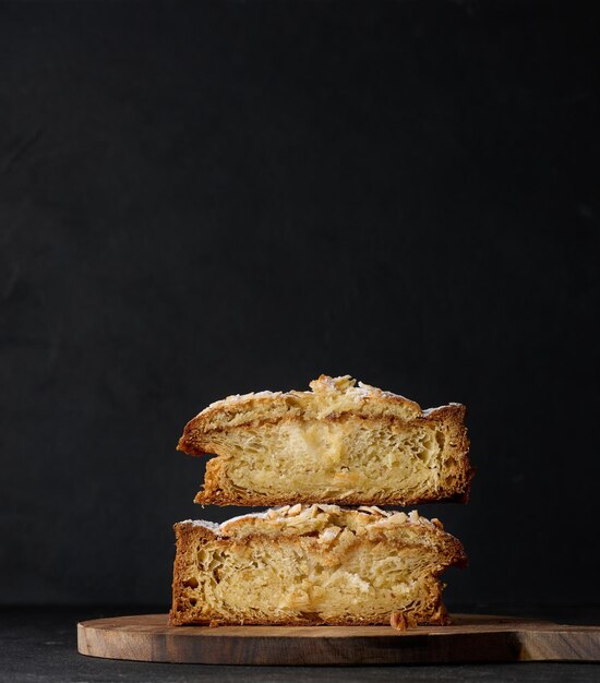 Round pastry with almonds and butter sprinkled with powdered sugar on the table puff pastry