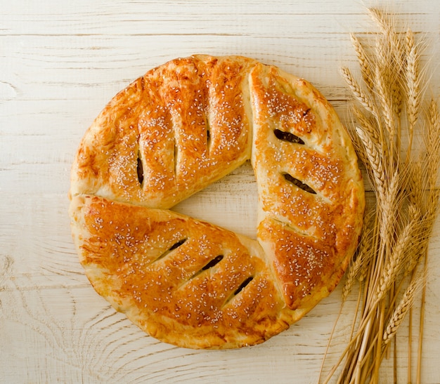 Round pie with sesame seeds, ears of wheat