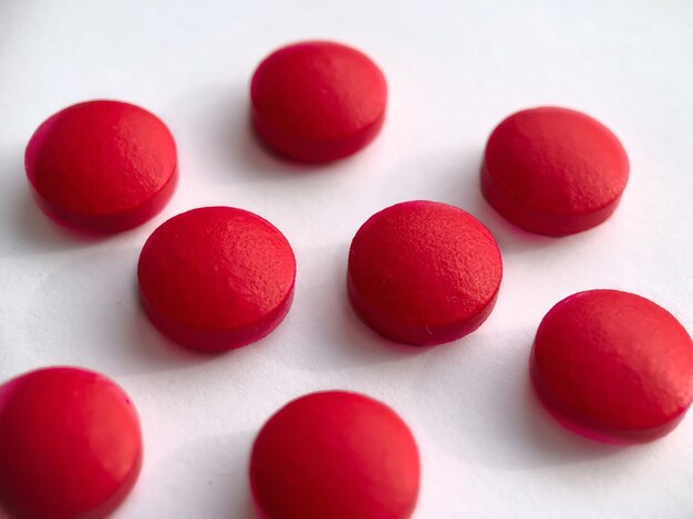 Pillole rotonde di colore rosso isolato su priorità bassa bianca. concetto di salute.