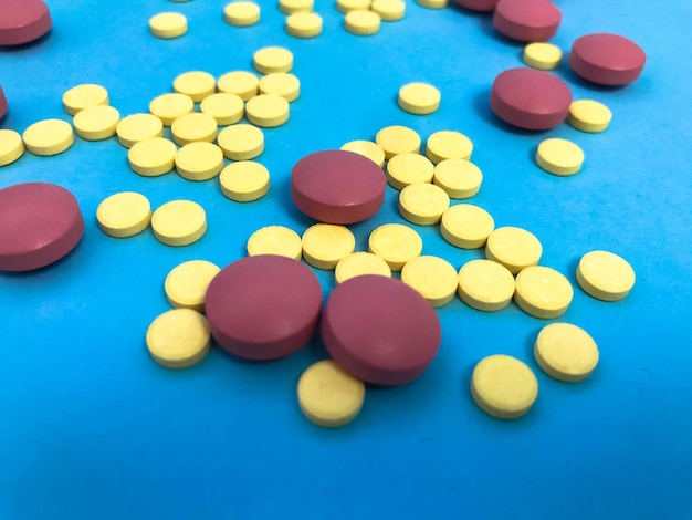 Round pink and yellow pills volumetric structure on a blue matte background health medications