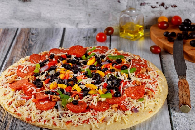 Round pizza with pepperoni, sausage, olives, pepper and cheese.