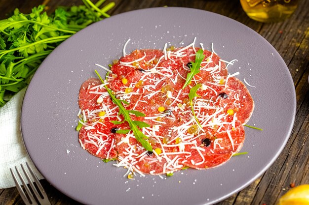 Photo round plate, appetizer stroganina from marbled beef with goat cheese and caviar, cold cuts