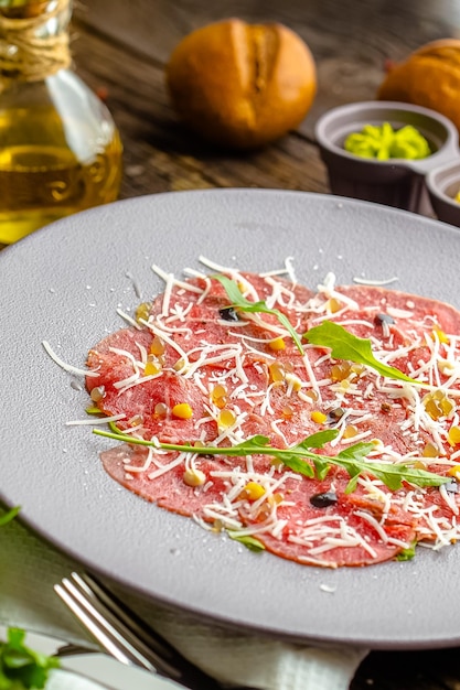 Photo round plate, appetizer stroganina from marbled beef with goat cheese and caviar, cold cuts