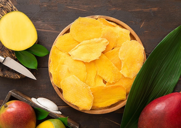 Round plate with dried mango pieces with knife and raw fruits