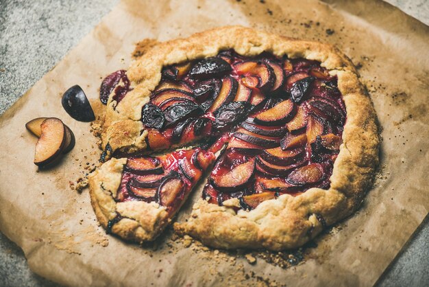 Round plum galetta cake on baking paper over concrete background