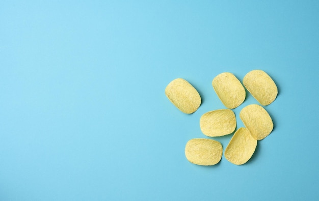 Round potato chips on a blue background, top view