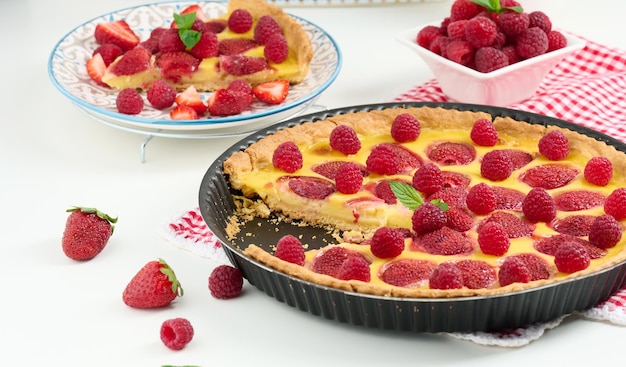 Round quiche with red strawberries and raspberries on a white table