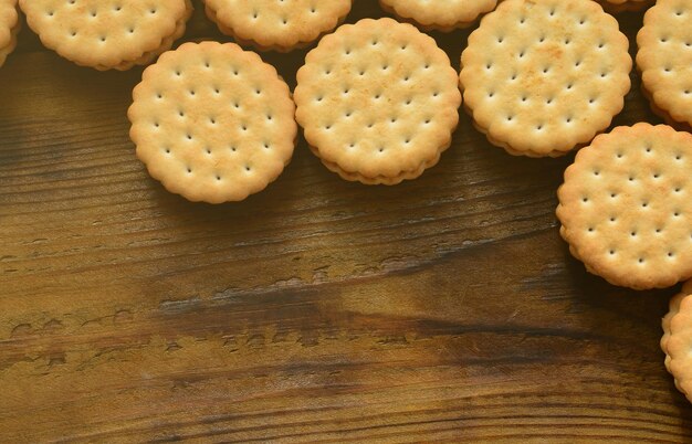 Photo a round sandwich cookie with coconut filling lies in large quantities on a brown wooden surface