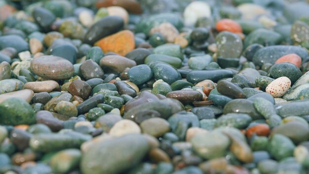 Round sea pebbles are washed by clean transparent sea waves small sea foam waves close up