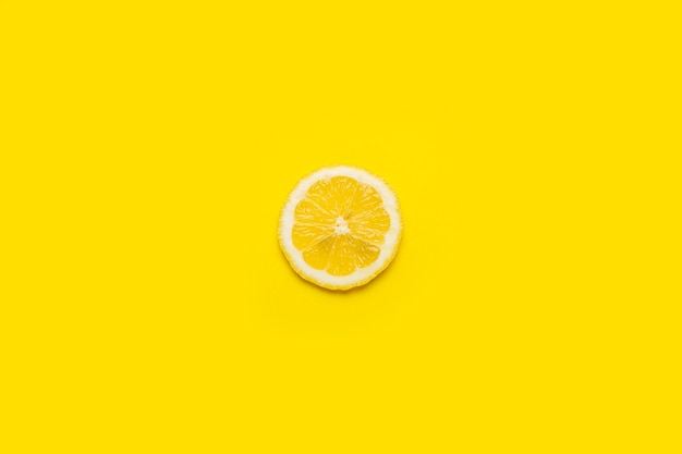 Round slice of yellow lemon on a yellow background Top view flat lay