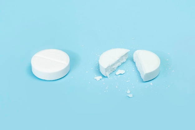 Round tablet was divided equally Two pills on a blue background medicineone tablet is broken in half