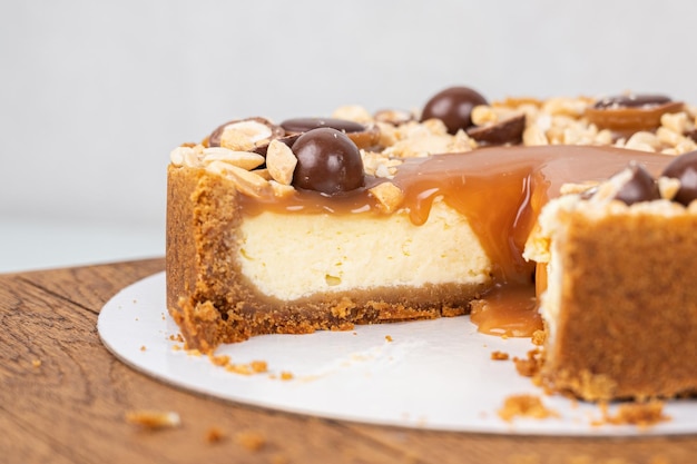 Round tart with salted caramel and nuts in section closeup Piece of cake on wooden stand Homemade baking concept