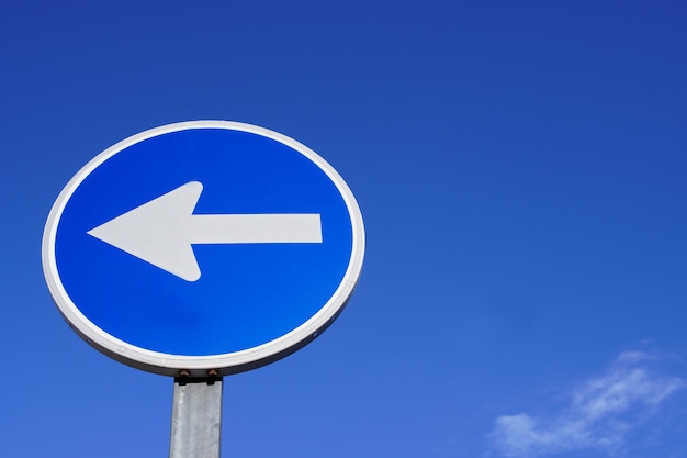 Round traffic sign with arrow over blue sky