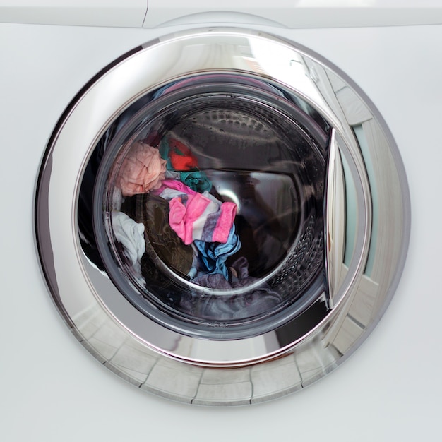 Foto lavatrice automatica con sportello tondo trasparente e il lavaggio della biancheria colorata.