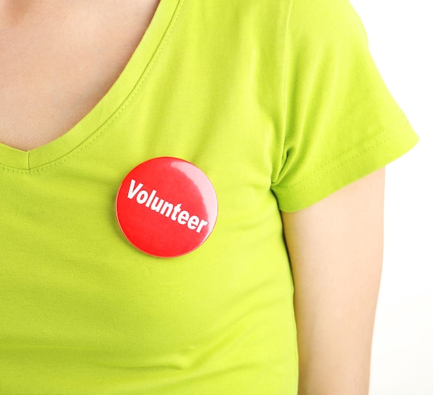 Photo round volunteer button on shirt of girl isolated on white