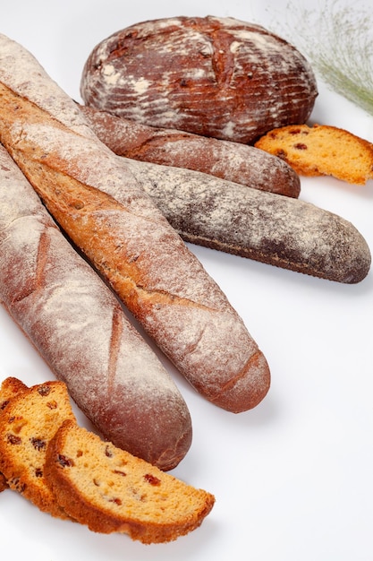 Round wheat bread, baguettes and sweet raisin cake slices of isolated on white