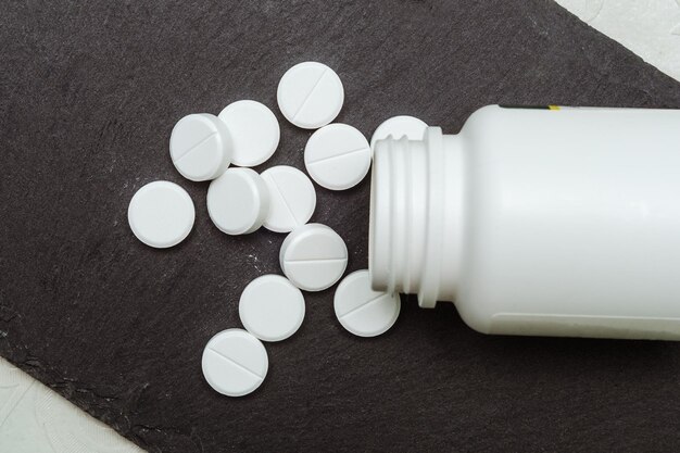 Round white pills near jar top view