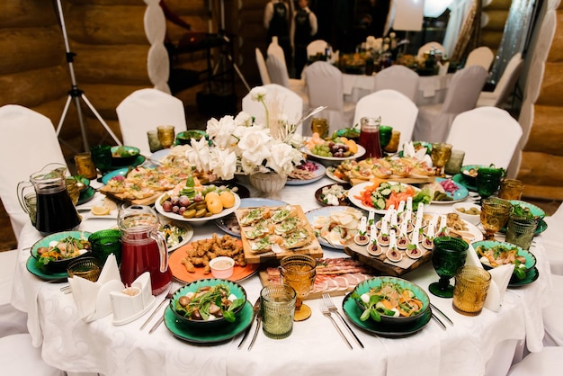 The round white table is filled with a large amount of food and various snacks in a luxurious interior beautiful serving of the holiday table