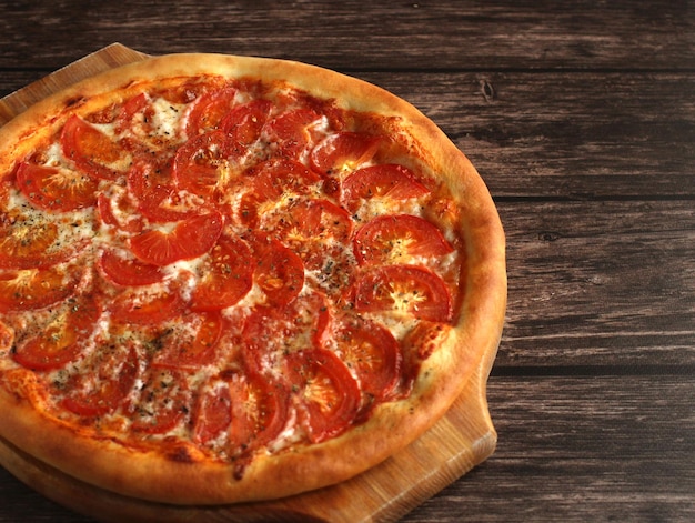 Round whole pizza margarita with tomatoes cheese and spices on a wooden dark background