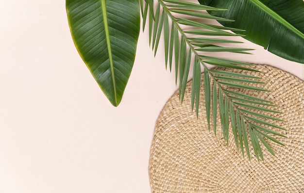 Round wicker stand and palm leaves on pink wall