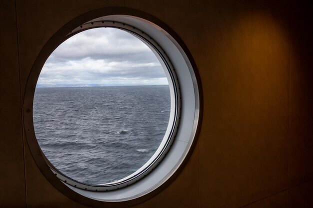 Round window on a ship looking outside onto the Atlantic Ocean