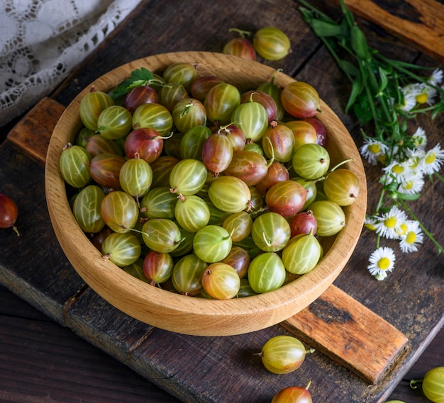 Round wooden bowl with green gooseberries