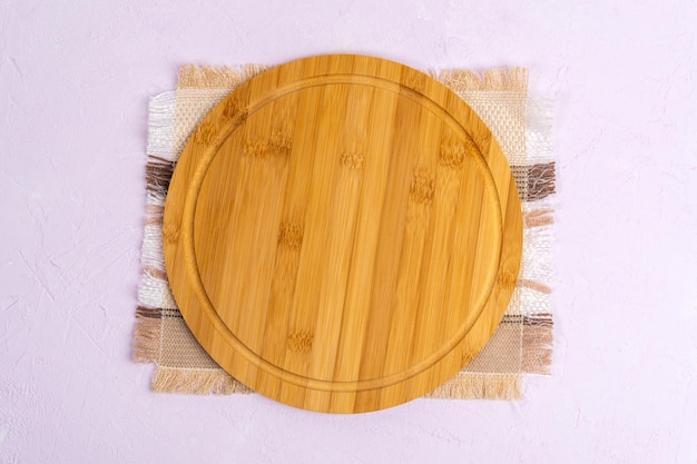Round wooden cutting board on light concrete background Flat lay