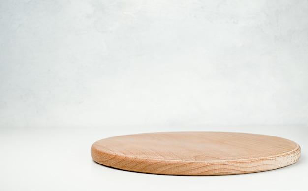 밝은 회색 테이블에 복사 공간이 있는 둥근 나무 커팅 보드