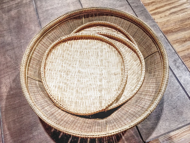 Photo round woven bamboo stripes trays on a wooden plank bench