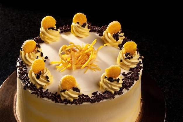 Круглый желтый торт ко дню рождения декоративные кремовые украшения на черном фоне торта