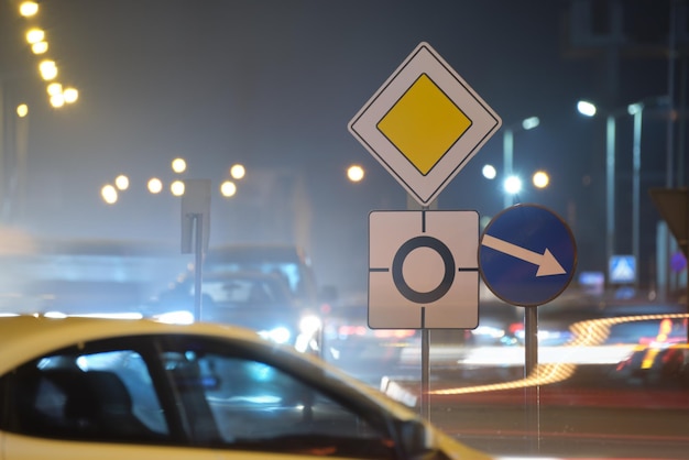 밤에 도시 거리 교통에 흐릿한 자동차가 있는 원형 교차로 표지판. 도시 교통 개념
