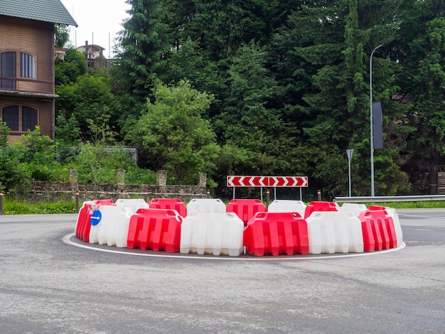 道路に白と赤のプラスチック製の障壁があるラウンドアバウト道路の建設プラスチック製の交通障壁赤白い交通用の水障壁が建設現場に配置されています