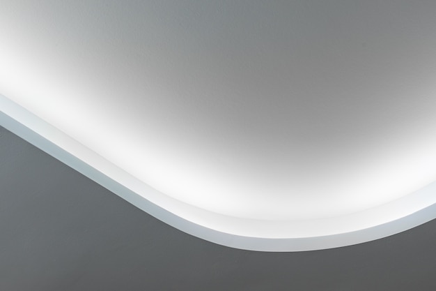 Rounded corner of the white walls and drywall suspended ceiling\
with integrated led lighting