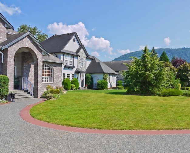 Rounded driveway and lawn in front of residential house on blue sky background