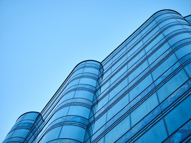Edificio per uffici di vetro arrotondato su una priorità bassa della prospettiva del cielo blu